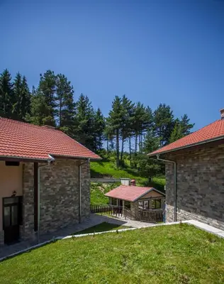 two buildings with red roofs and a yard at Ваканционна къща ,,Родопски уют 