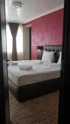 a bedroom with a large bed with a pink wall at Central Guest Rooms in Asenovgrad