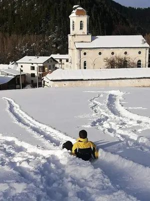 a person is sitting in the snow in front of a building at Guest House Lorian in Madzhare