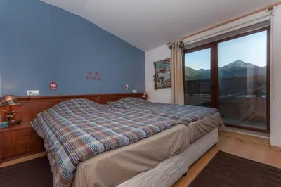 a bedroom with a bed and a large window at Mountain Paradise 4 Apartments in Bansko