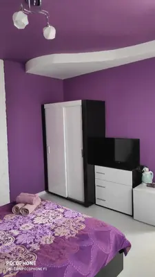 a purple bedroom with a bed and a tv at Georgievi Guest House in Sapareva Banya