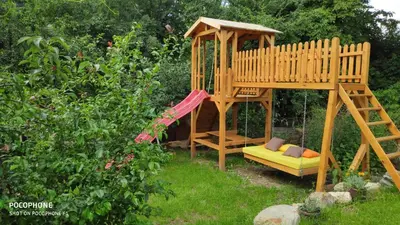 a wooden play house with a slide and a bench at Georgievi Guest House in Sapareva Banya