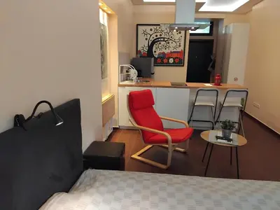 a bedroom with a red chair and a kitchen at Embassy Apartment in Sofia