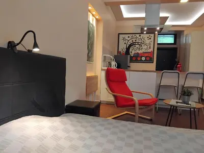 a bedroom with a red chair and a kitchen at Embassy Apartment in Sofia