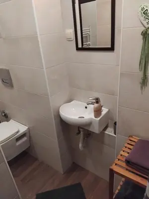 a white bathroom with a sink and a mirror at Embassy Apartment in Sofia