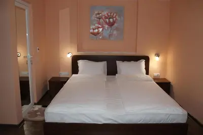 a bedroom with a large white bed with a painting on the wall at Center Guest House in Sapareva Banya
