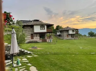 a house with a yard with an umbrella and a playground at Leshten Guest Homes in Leshten