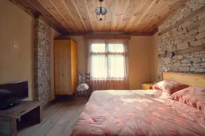 a bedroom with a bed and a stone wall at Leshten Guest Homes in Leshten