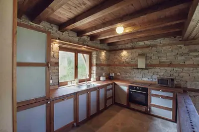 a kitchen with wooden walls and a stone wall at Leshten Guest Homes in Leshten