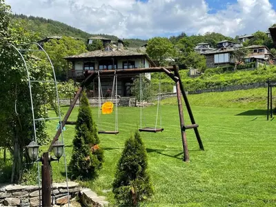 a swing set in a yard with a house at Leshten Guest Homes in Leshten