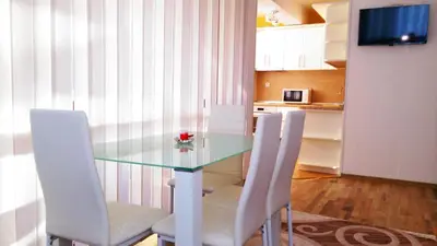 a glass table and white chairs in a room at United Apartments in Sandanski