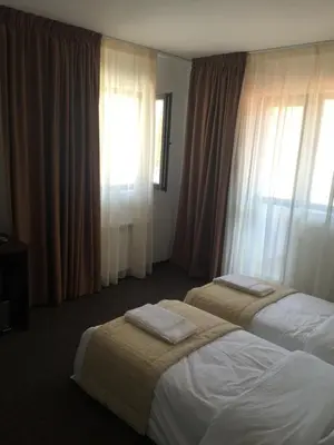 two beds in a hotel room with windows at Park Hotel Eagle Stone in Koprivshtitsa