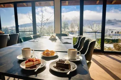 a table with two plates of cake and cups of coffee at Park Hotel Eagle Stone in Koprivshtitsa