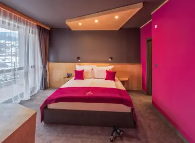 a bedroom with a large bed with pink walls at Hotel Arte SPA & Park in Velingrad