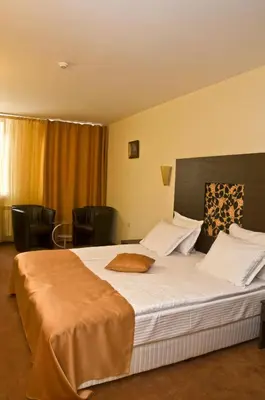 a bedroom with a large bed in a room with chairs at Hotel 4 Zona in Sofia