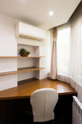 a white chair sitting next to a desk with a window at Lozenets Apartment in Sofia
