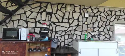 a kitchen with a stone wall with a microwave at Danailovi Guest House in Sapareva Banya