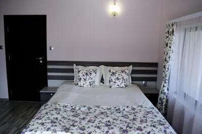 a bedroom with a bed with a floral bedspread and pillows at Family Hotel Neliya in Velingrad