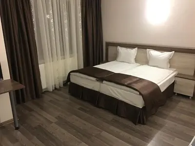 a bedroom with a bed with white sheets and pillows at Family Hotel Neliya in Velingrad