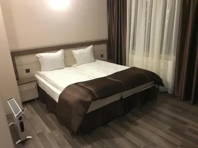 a hotel room with a bed with white sheets and pillows at Family Hotel Neliya in Velingrad