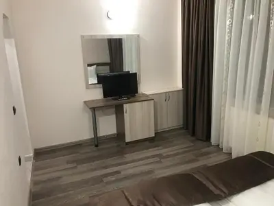 a room with a television on a table and a mirror at Family Hotel Neliya in Velingrad