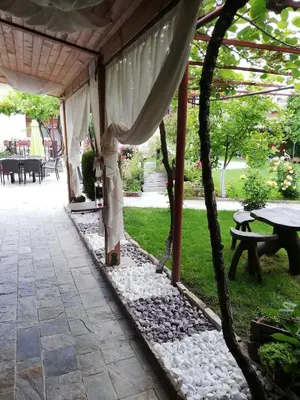 a covered patio with a table and a tree at Family hotel Gradina in Ognyanovo
