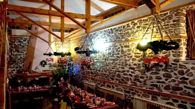 a restaurant with a stone wall with tables and chandeliers at Family hotel Gradina in Ognyanovo