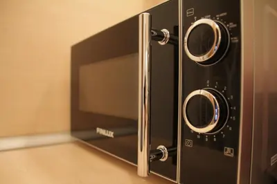 a black microwave oven with two knobs on it at Apartment 132 in Sofia