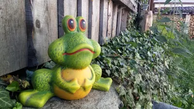 a frog statue sitting on a rock next to a fence at Villa Lyutovi Holiday Home in Koprivshtitsa