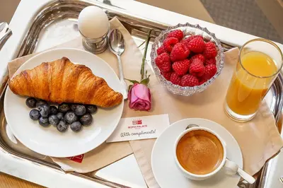 a tray with a plate of fruit and a cup of coffee at Sofia Palace Hotel by HMG in Sofia