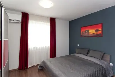 a bedroom with a bed and a window with red curtains at Sofia Top Apartments in Sofia