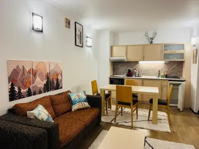 a living room with a couch and a table and a kitchen at Stenata Huge Ski To Door Apartments in Pamporovo