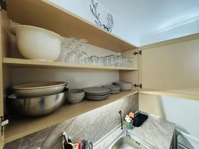 a kitchen with plates and bowls on shelves and a sink at Stenata Huge Ski To Door Apartments in Pamporovo