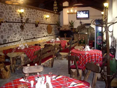 a restaurant with tables and chairs and a tv at Popsokol House in Bratsigovo