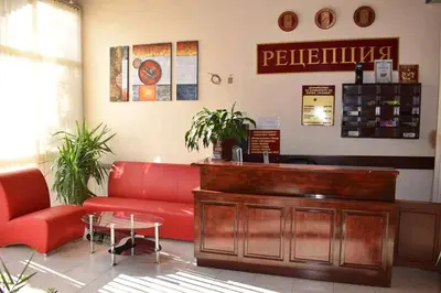 a waiting room with a red couch and a counter at Hotel Trakia in Plovdiv