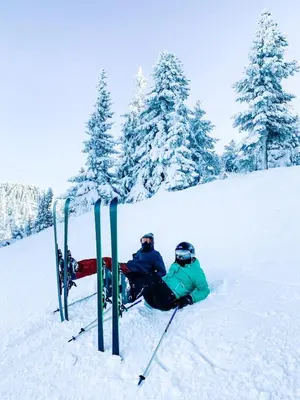 two people sitting on a snow covered slope with skis at Chalet Mechka in Borovets