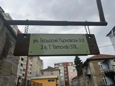 a sign hanging from a pole in a city at City Garden Studio in Plovdiv