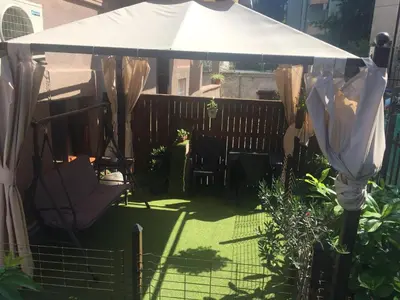 a patio with a white umbrella and chairs under a fence at City Garden Studio in Plovdiv