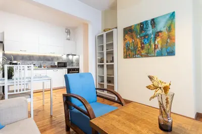a kitchen and living room with a table and blue chairs at Rentapart Step in Sofia