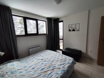 a bedroom with a bed and a large window at Denitsa Apartment in Borovets