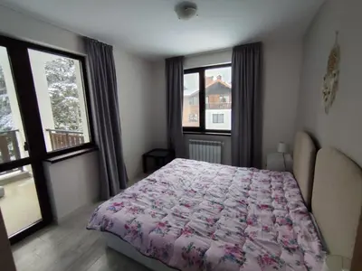 a bedroom with a bed and two windows at Denitsa Apartment in Borovets