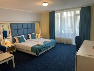 a hotel room with a large bed and a desk at Hotel Forum in Pazardzhik