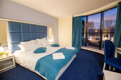 a hotel room with a large bed and a large window at Hotel Forum in Pazardzhik