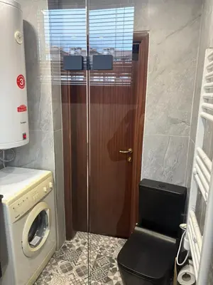 a bathroom with a washing machine and a wooden door at Ramada 2 Boutique Apartment near Ski Road in Bansko