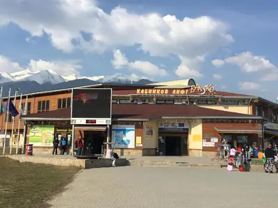 a building with a sign on it with mountains in the background at Ramada 2 Boutique Apartment near Ski Road in Bansko