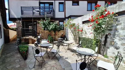an outdoor patio with tables and chairs and flowers at Kadiyata Guest House in Bansko