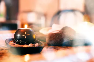 a candle sitting on a table with a bowl of peanuts at Balneo & SPA Hotel Aura in Velingrad