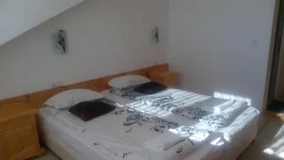 a bedroom with a bed with white sheets and pillows at Guest House Garbevi in Dobrinishte