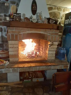 a brick fireplace with a fire in it at Guest House Garbevi in Dobrinishte