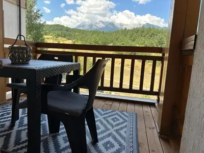 a table and chair on a balcony with a view of mountains at PM Mountain View Fireside Retreat Bansko in Bansko